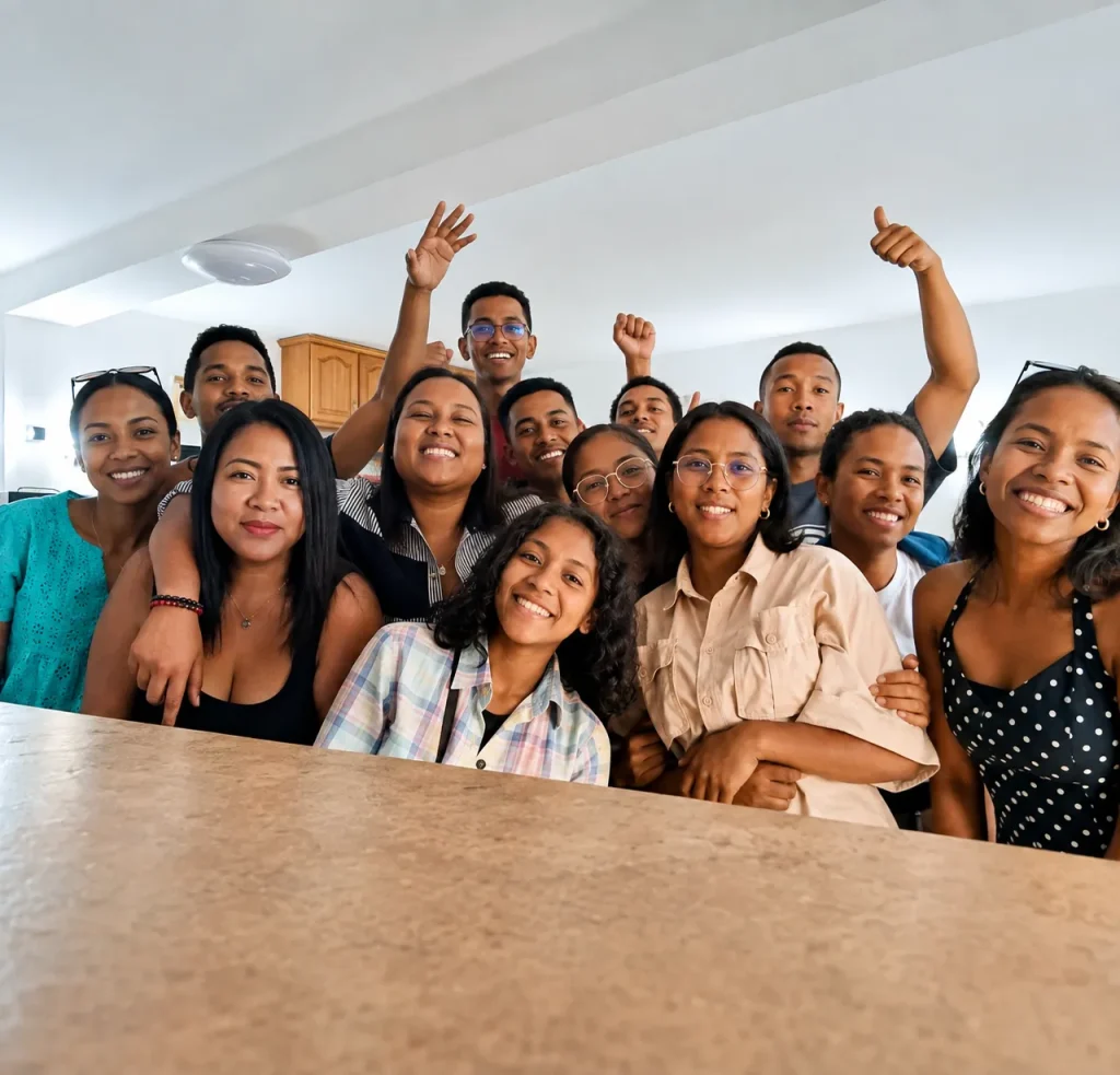 Groupe de jeunes souriants posant ensemble dans un intérieur lumineux, exprimant joie et camaraderie.